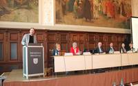 Lutz Heimann steht links im Bild am Rednerpult und spricht. Rechts neben ihm sitzen die Kreistagsvorsitzenden, Landrat Hartmut Handschak und die Dezernentinnen.
